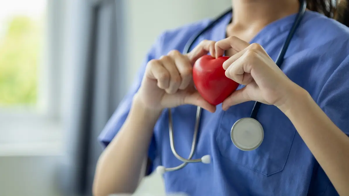 beautiful young woman doctor in medical uniform holding a plastic heart