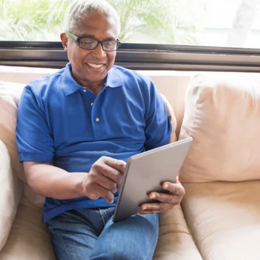 senior man sitting on sofa using tablet senior man sitting on sofa using tablet